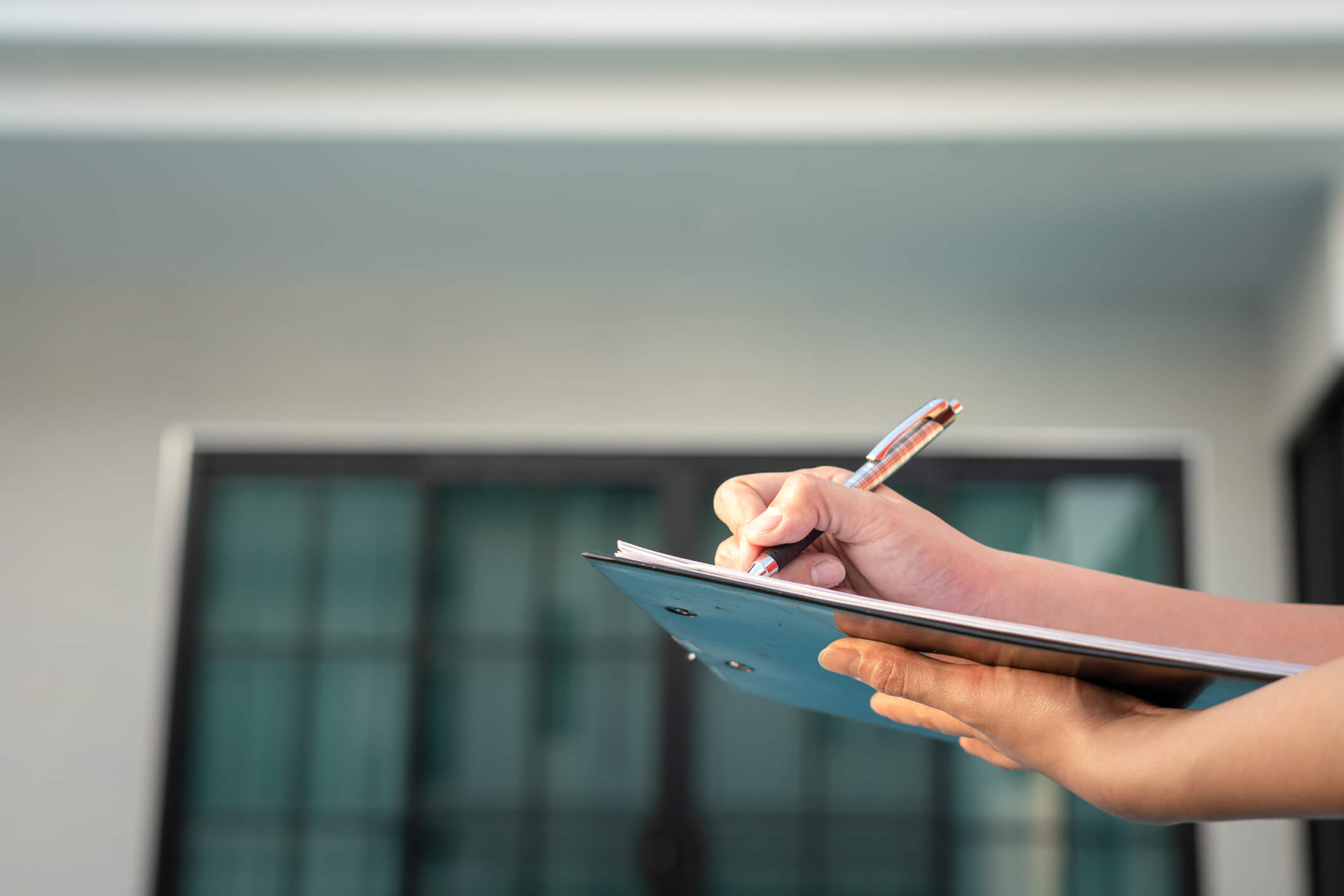 Roofing and siding expert is writing down on the clipboard paper to verify the quality of the roofing and siding